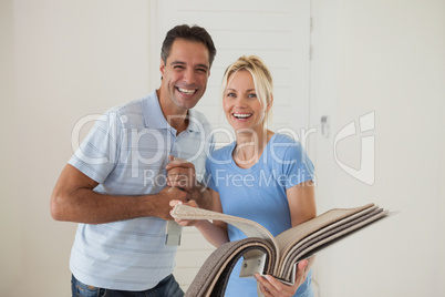 Portrait of a happy couple with color book in new house