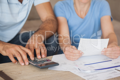 Mid section of a couple with bills and calculator