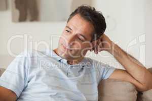 Close-up of a thoughtful man sitting on sofa