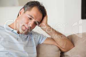 Close-up of a thoughtful man sitting on sofa