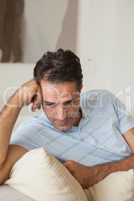 Close-up of a thoughtful man sitting on sofa