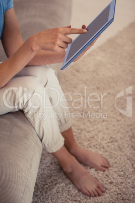 Low section of a young woman using digital tablet