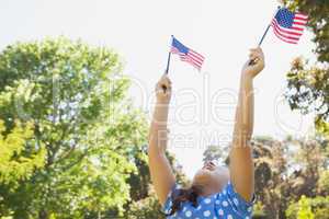 Girl holding up two American flags at park
