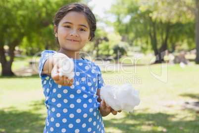 Beautiful little girl holding cotton candy at park