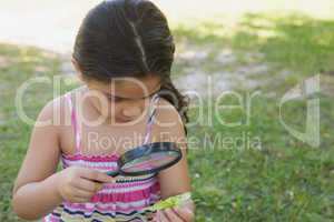 Girl examining a leaf with magnifying glass at park