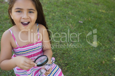 Girl examining a butterfly with magnifying glass at park