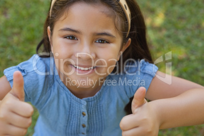 Young girl gesturing thumbs up at park