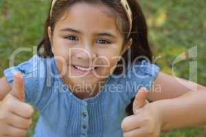 Young girl gesturing thumbs up at park