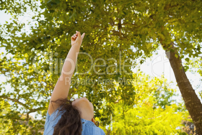 Young girl pointing up at trees in park