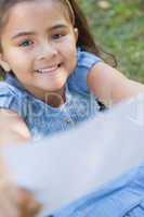 Smiling girl holding out a blurred paper at park
