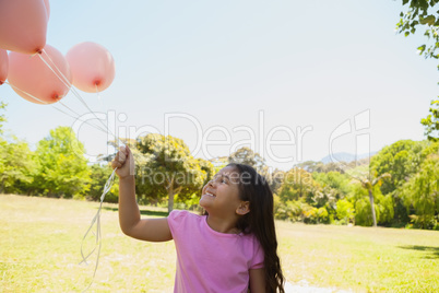 Girl playing with pink balloons at park