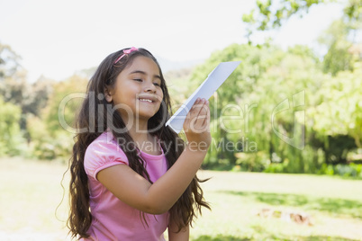 Girl playing with a paper plane at park