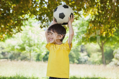 Little boy holding up football at park