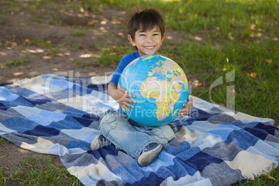 Cute young boy holding globe at park
