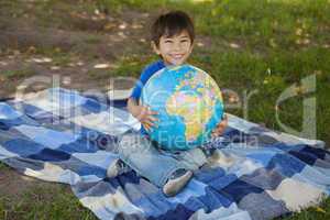 Cute young boy holding globe at park