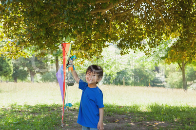 Happy young boy holding kite at park