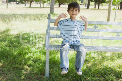 Happy young boy sitting on bench at park