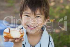 Happy young boy hyolding burger at park