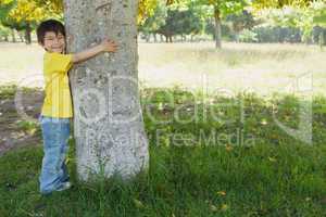 Young boy hugging a tree at park