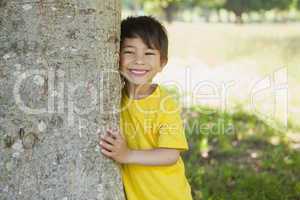 Cheerful boy standing by tree at park