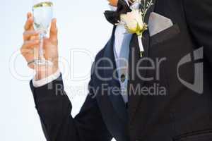 Mid section of flowers on lapel of male as he holds champagne gl