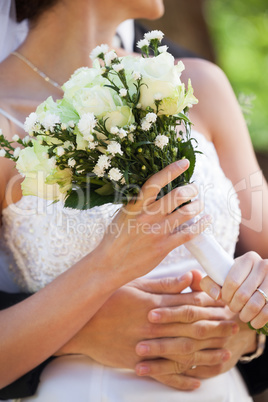 Mid section of a newlywed couple with bouquet in park