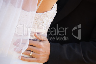 Mid section of newlywed couple embracing