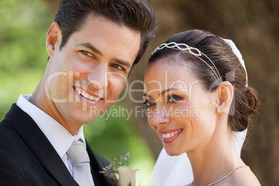 Happy newlywed couple looking away at park