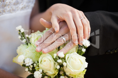 Newlywed couple with wedding rings and bouquet