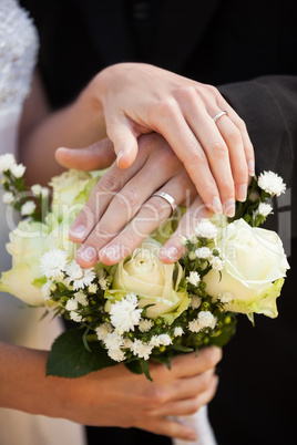 Newlywed couple with wedding rings and bouquet