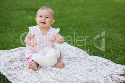 Cute baby sitting on blanket at park