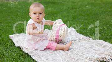 Cute baby sitting on blanket at park