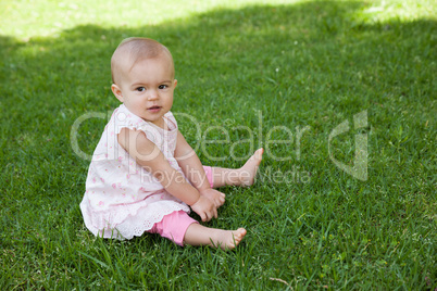 Cute baby sitting on grass at park