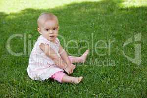 Cute baby sitting on grass at park