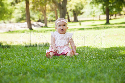 Happy cute baby sitting on grass at park