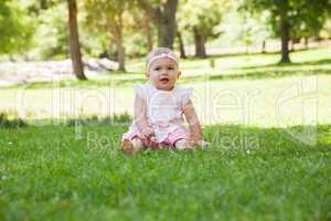 Happy cute baby sitting on grass at park