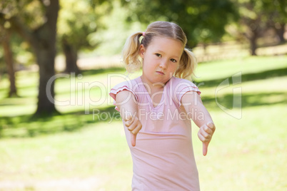 Displeased girl gesturing thumbs down at park