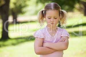 Sad young girl with arms crossed at park