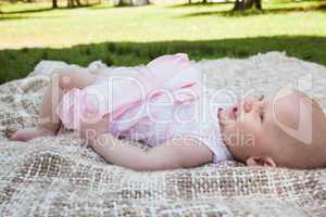Side view of a cute baby lying on blanket at park