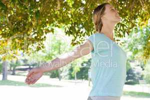 Smiling woman with arms outstretched at park