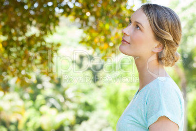 Serious young woman looking at leaves in park