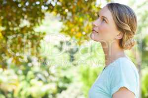 Serious young woman looking at leaves in park