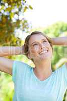 Happy thoughtful young woman looking up in park