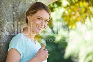 Happy woman gesturing thumbs up at park