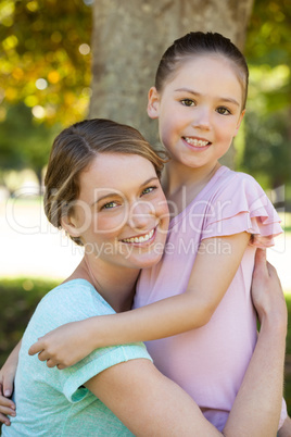 Smiling mother embracing her daughter at park Smiling mother embracing her daughter at park