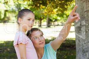 Mother pointing at something besides daughter at park