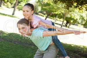 Happy mother carrying daughter at park