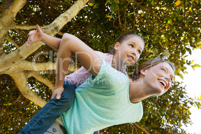 Happy mother carrying daughter at park