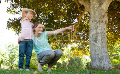 Mother pointing out at something besides daughter at park