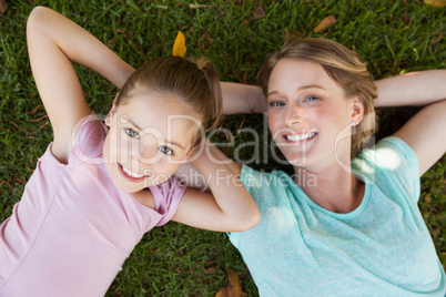 Happy mother and daughter lying on grass at park